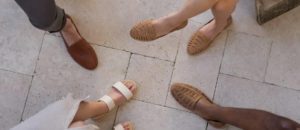 A group of people standing in a circle wearing sandals during an Amazon marketing management session.