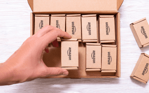 A hand reaching into a box of Amazon boxes for marketplace management.