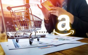 A woman is sitting at a desk managing her Amazon seller central account with a shopping cart in front of her.